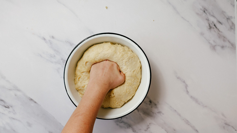 Punching risen dough in bowl