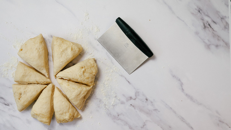 Dough cut into 8 triangles and bench scraper