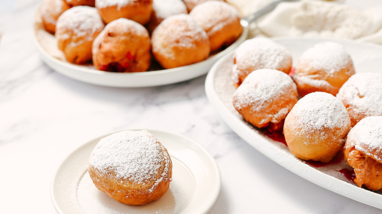 Plate full of raspberry sufganiya on a plate with more in background