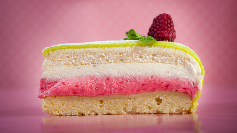 A slice of princess cake on a pink background