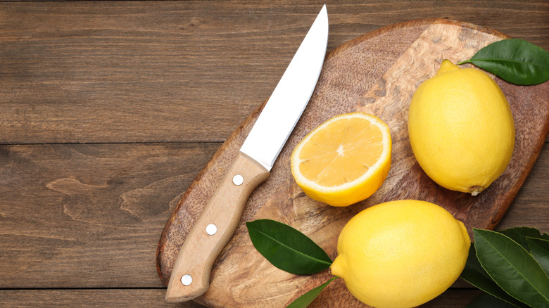 Lemons on a wooden board with a knife