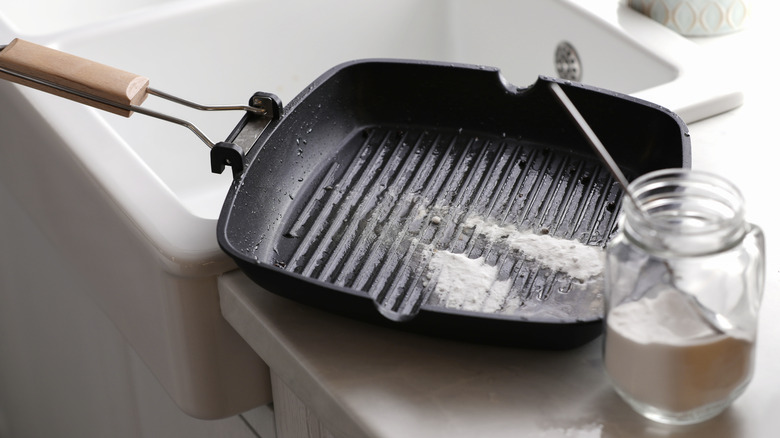 A person cleaning a cast iron pan with baking soda