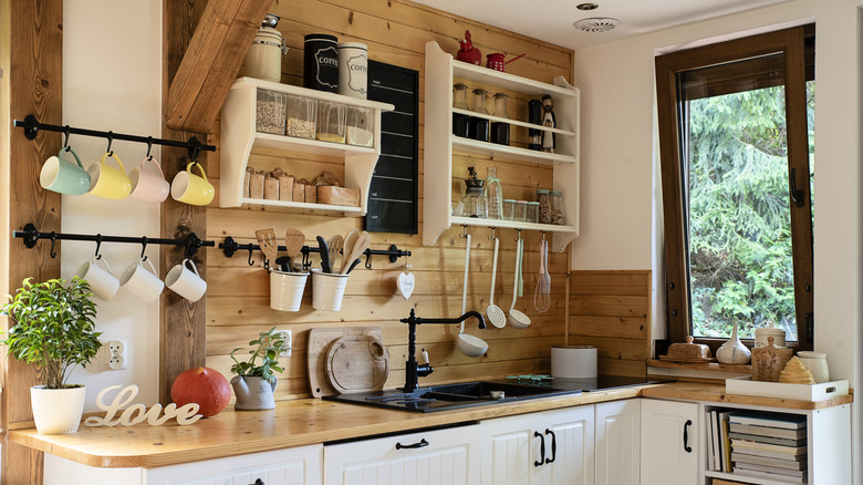 Interior of a farmhouse-style kitchen with lots of wood accents, pots and pans hanging from the walls, and spices on the shelves.