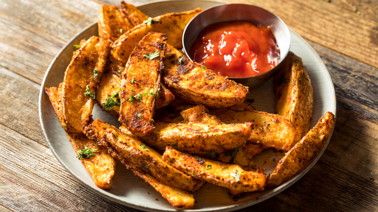 Overhead view of spiced baked fries on a plate with ketchup