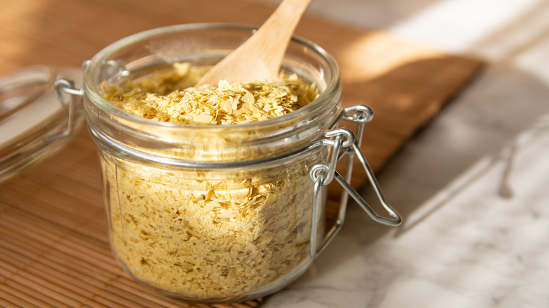 Closeup of jar of nutritional yeast and a wooden spoon