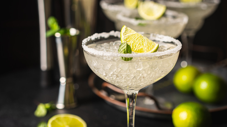 Close-up of a margarita cocktail in a glass, garnished with a lime wedge and mint leaf