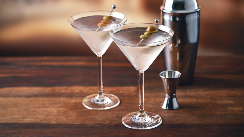 Two martini cocktails in glasses, each garnished with olives on skewers