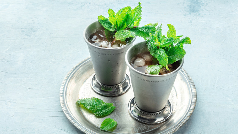 Two mint julep cocktails in silver julep cups on a silver platter
