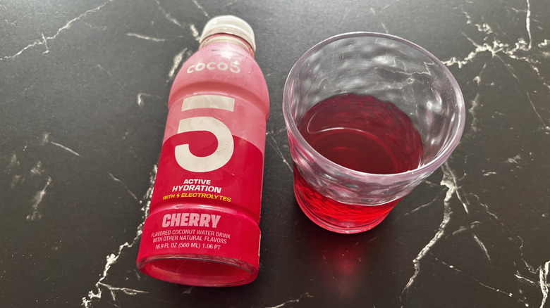 Cherry Coco5 bottle next to red liquid in glass