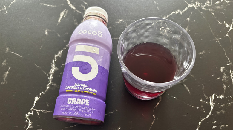 Grape Coco5 coconut water bottle next to purple liquid in cup
