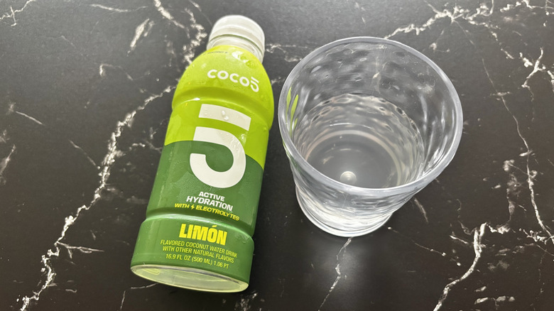 Limon Coco5 coconut water bottle next to liquid in cup