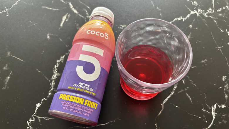 Passion fruit Coco5 coconut water bottle next to red liquid in cup