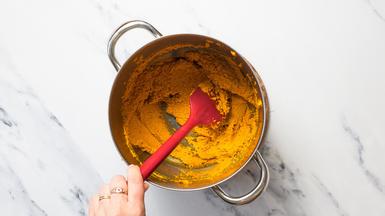 Stirring curry paste in pot with oil.