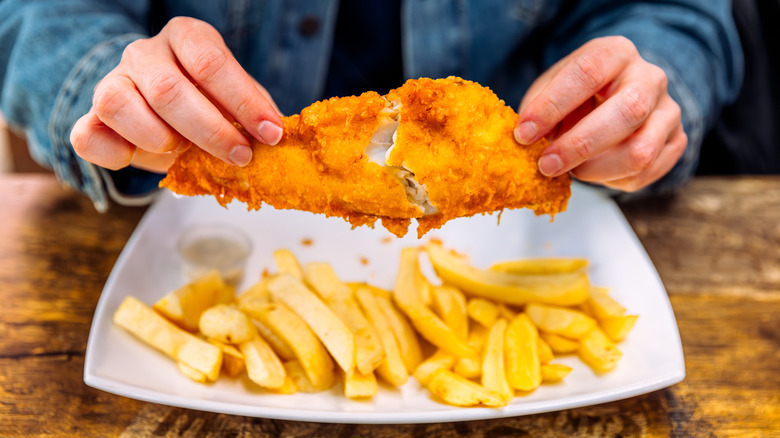 Person eating fried cod and chips