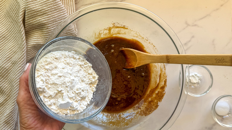 hand adding flour to bowl