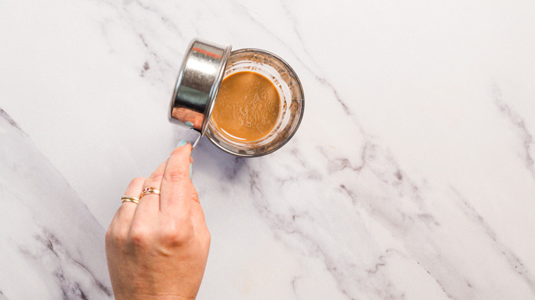Adding milk to glass with brown egg cream mixture