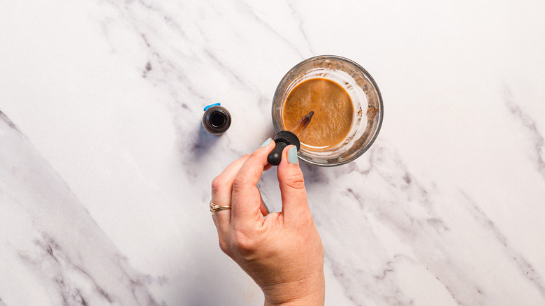 Adding bitters to glass with brown egg cream mixture