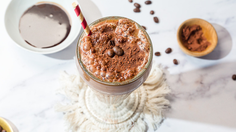 Overhead view of glass with frothy egg cream with red and white straw