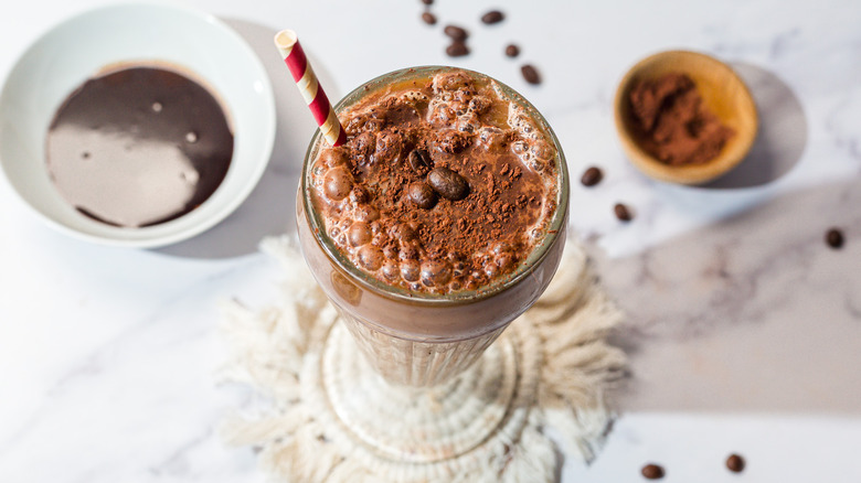 Overhead view of glass with frothy egg cream with red and white straw