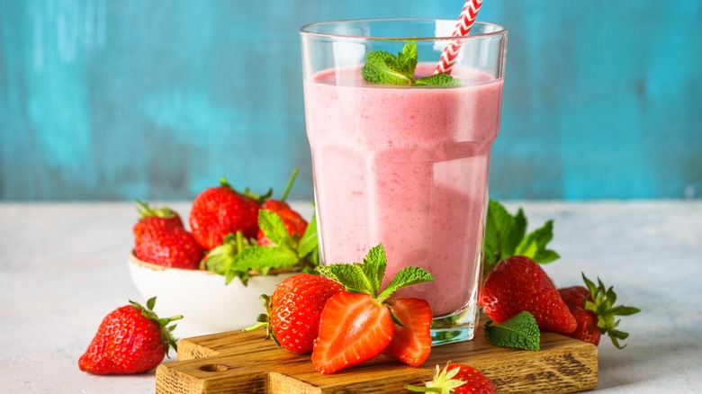 A pink fruit smoothie with whole strawberries