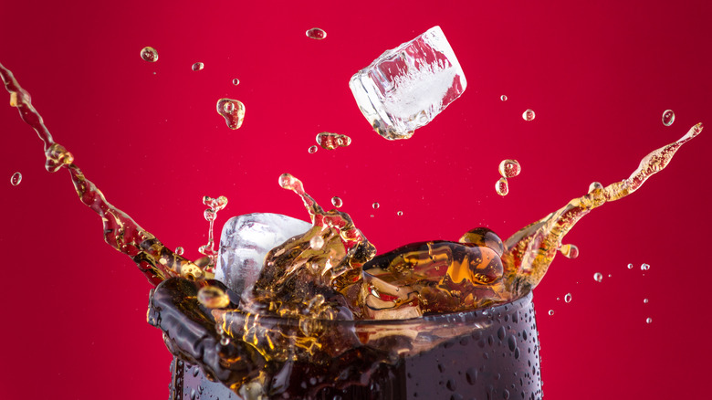 Ice cubes dropping into a glass of Coca-Cola