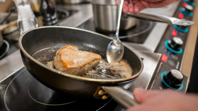 butter basting a pork chop on the stove