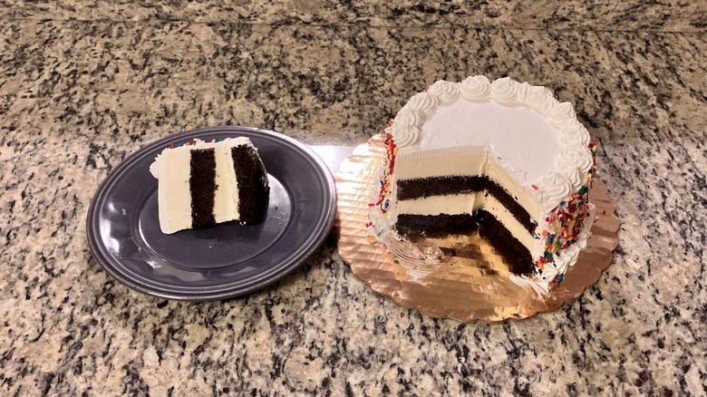 A slice of Cold Stone Creamery's birthday cake sits on a purple plate to the left while the rest of the cake sits on a gold plate on the right