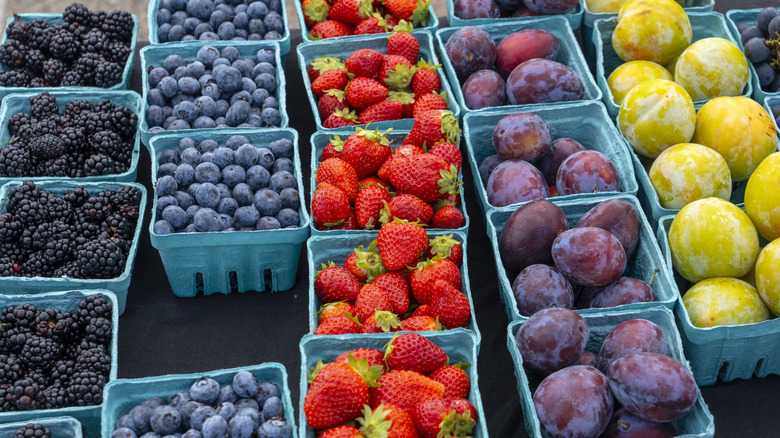 Overhead view of cartons of fresh seasonal strawberries and other summer fruit