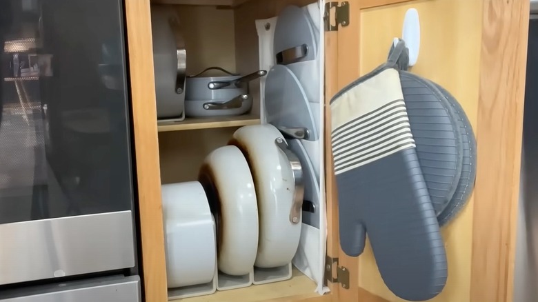 Command hook inside of a cupboard door holding an oven mitt and potholders