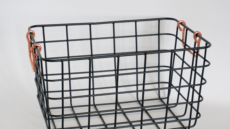 A black wire storage basket with bronze handles