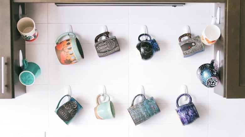 Mugs hanging off of Command hooks on kitchen backsplash