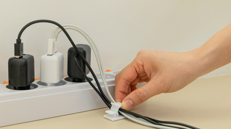 A hand hooks down charging cables to keep them neat