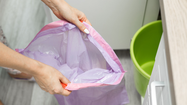 Two hands change out the liner of a trash can