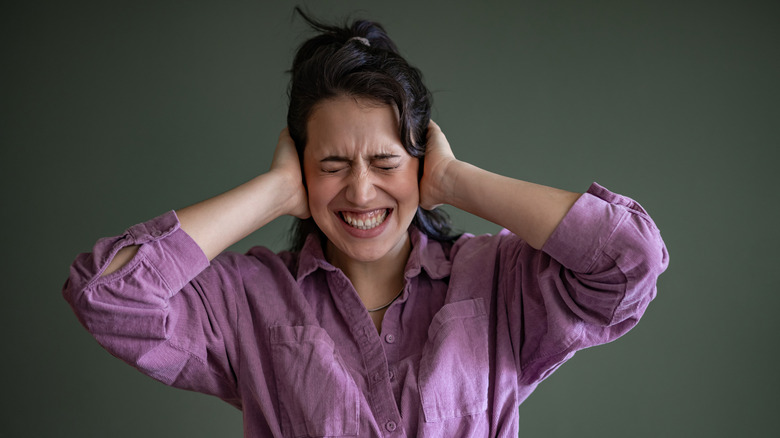 Woman holding her hands to her ears, grimacing