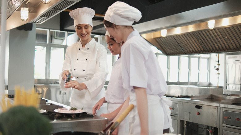 Two female culinary students (not the author) taking instruction from a female chef.