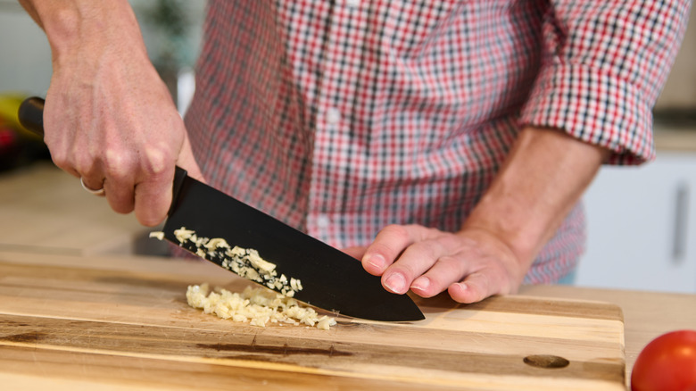 Person mincing garlic on a wood cutting board