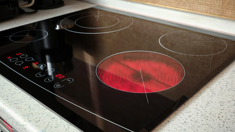 Modern glass cooktop with digital controls, with the large right-front burner glowing red to show that it's hot