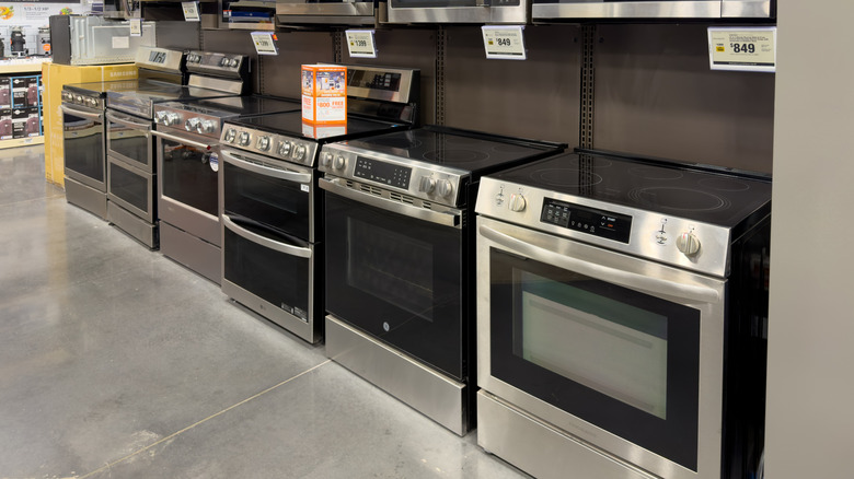 Retail store's display of electric stove ranges with stainless-steel accents and glass cooktops