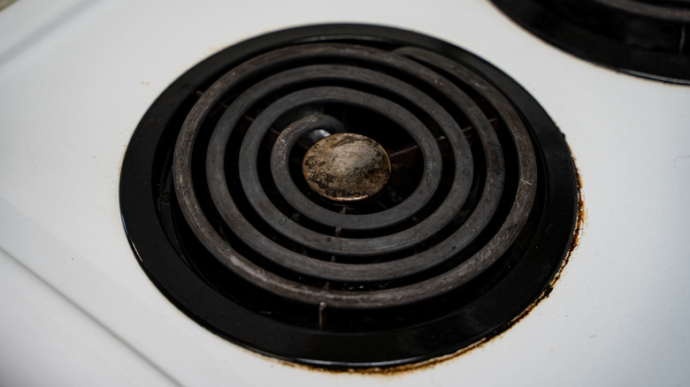 Grubby-looking electric coil burner on a white enameled cooktop