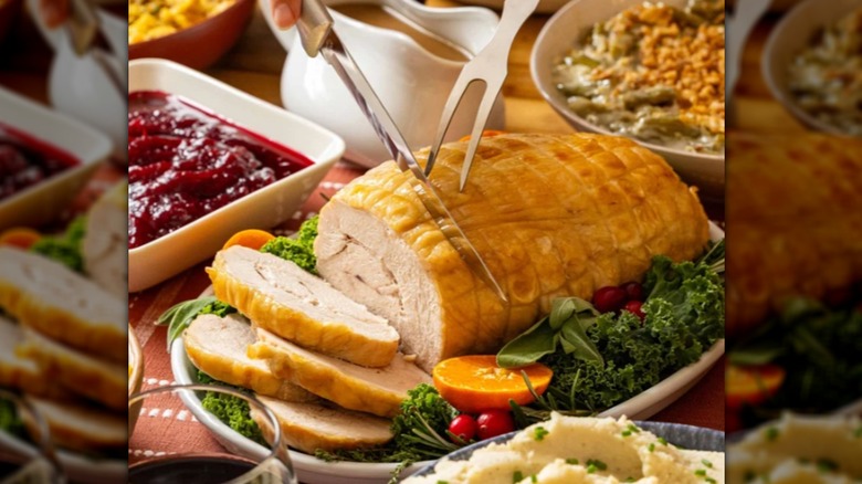 A person carving a Costco turkey with sides on the table