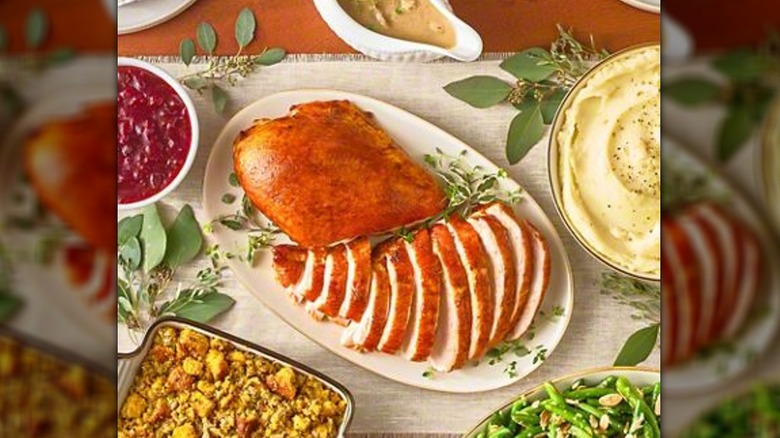 A partially-carved turkey on a platter next to sides