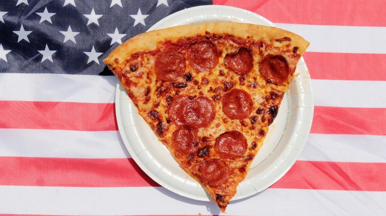 A slice of pepperoni pizza on a paper plate on an American flag