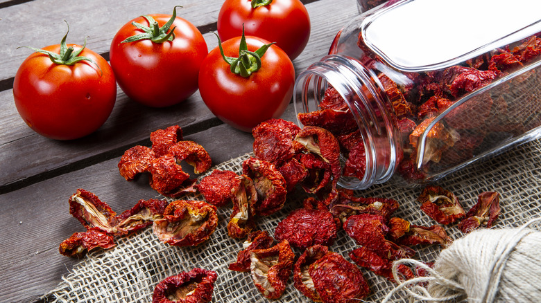 Fresh and sun-dried tomatoes on table