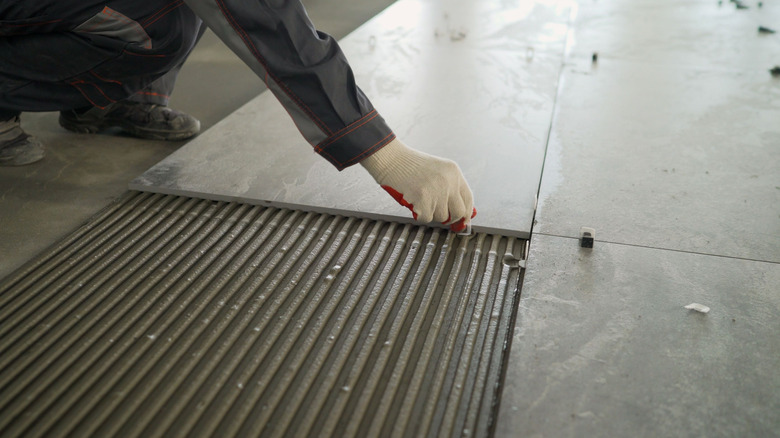 Person installing large stone floor tiles in the kitchen
