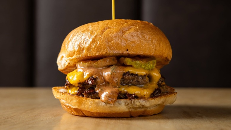A juicy cheeseburger on a table with a black background.