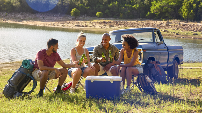A group of friends sitting around a cooler while camping