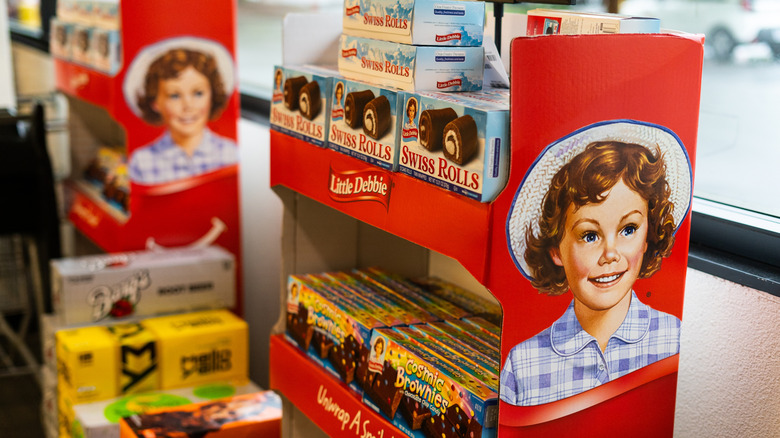 Little Debbie bumpout display made out of red cardboard with Swiss rolls and cosmic brownies on the shelf.