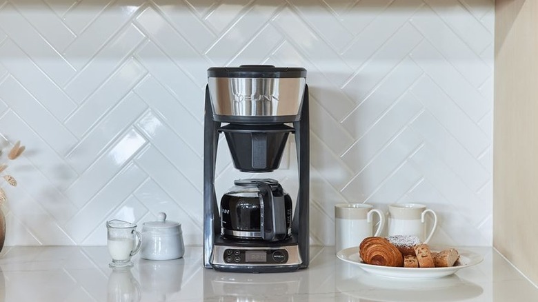 Bunn drip coffee maker displayed on a glossy white countertop, against a white backsplash.