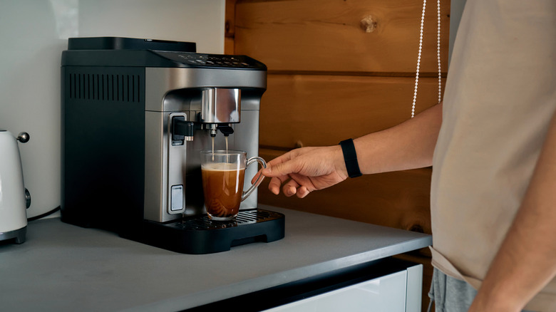 Man making himself a cup of coffee with a modern coffee machine.