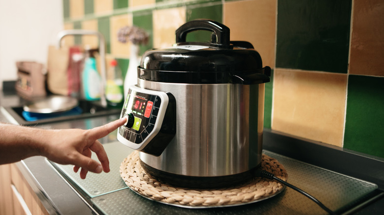 Person pressing button on slow cooker